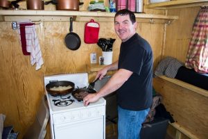 man cooking on stove in fish house