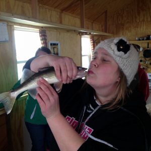 woman in hat kisses fish
