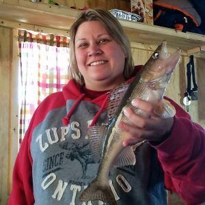 Woman holds fish after ice fishing