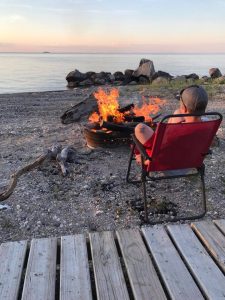 Boy sitting in red chair by campfire
