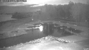 Black & White photo from webcam Red moon night shining in the sky and reflecting off the harbor water.